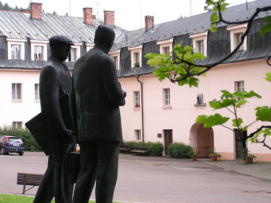 A sculpture of the Čapek brothers with their native house in the background, currently a museum